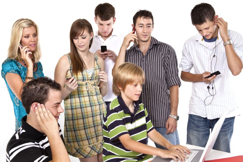 A group of teens devote their attention to cellphones and computers