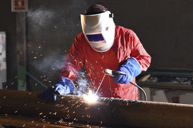 A worker relies on his FR wear to protect him while he welds