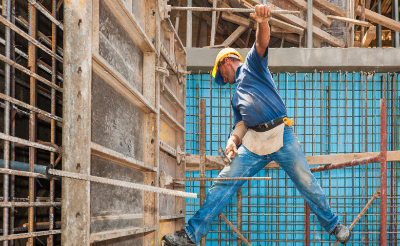 Construction worker balancing between scaffold and formwork frame, complacent to the risk