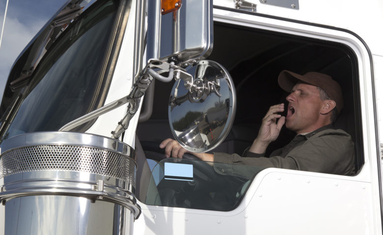 Tired trucker yawning at the wheel