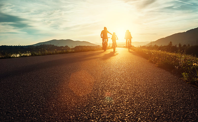 Сyclists family traveling on the road at sunset