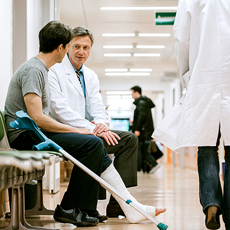 Man With Cruches And Cast On Broken Leg Consulting Doctor