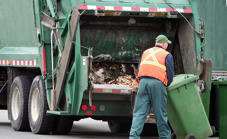 Waste collector preparing garbage bin for truck