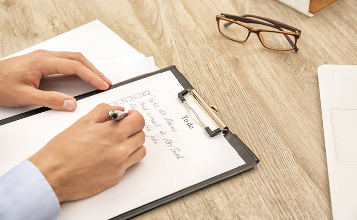 Man making to-do list while sitting at table, closeup