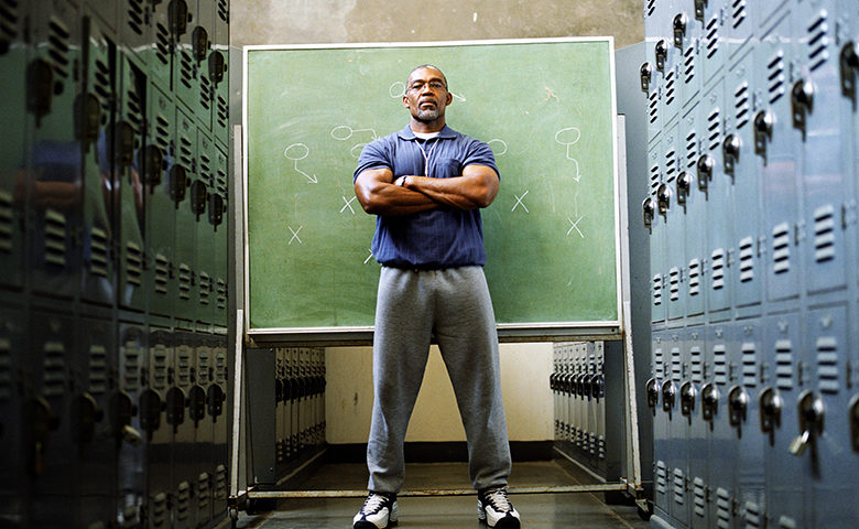Coach in locker room, standing in front of chalkboard