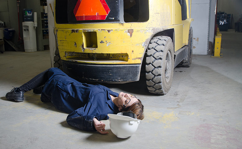 Injured woman worker on floor in front of vehicle