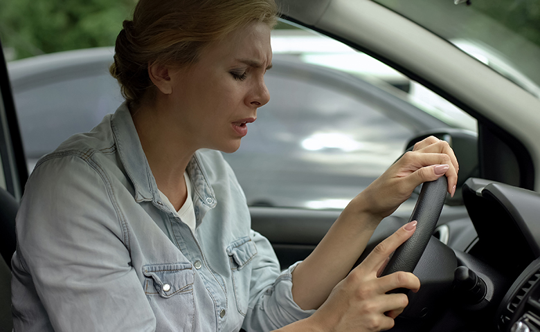 Woman experiencing pain or a problem while driving
