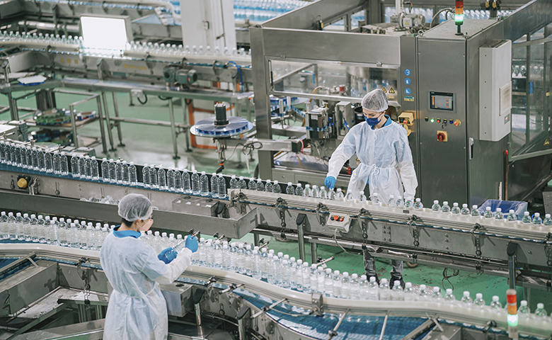 Factory production line workers with PPE examining water bottle working in daily routine