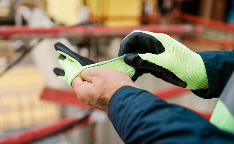 Worker at construction site putting on gloves.