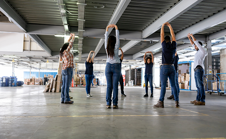 Group of employees taking a break to stretch while working at a warehouse