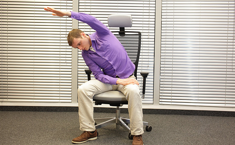 Man performing chair yoga in office chair