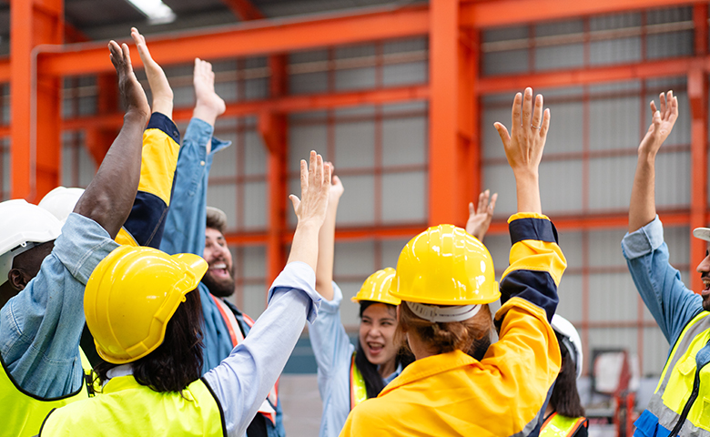 group of diverse workers raising hands to celebrate project success