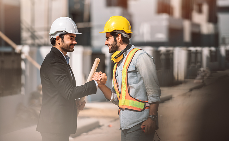 Supervisor and worker handshaking at construction site.