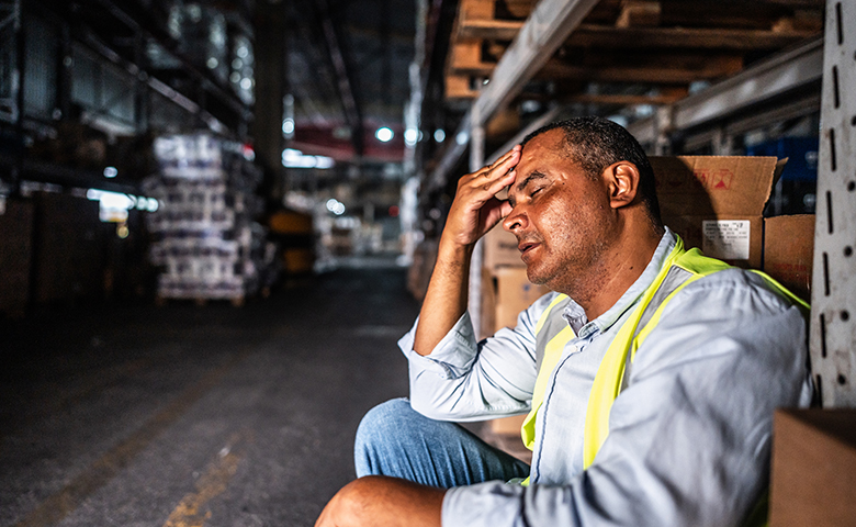 Tired man at work sitting in the warehouse