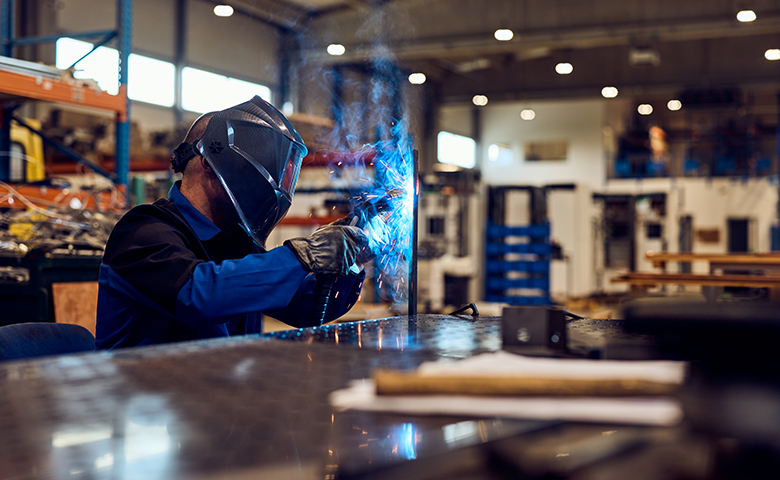 Welder Working in an Industrial Setting With Protective Gear and Bright Sparks